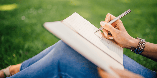 Woman sat in grass writing in a journal