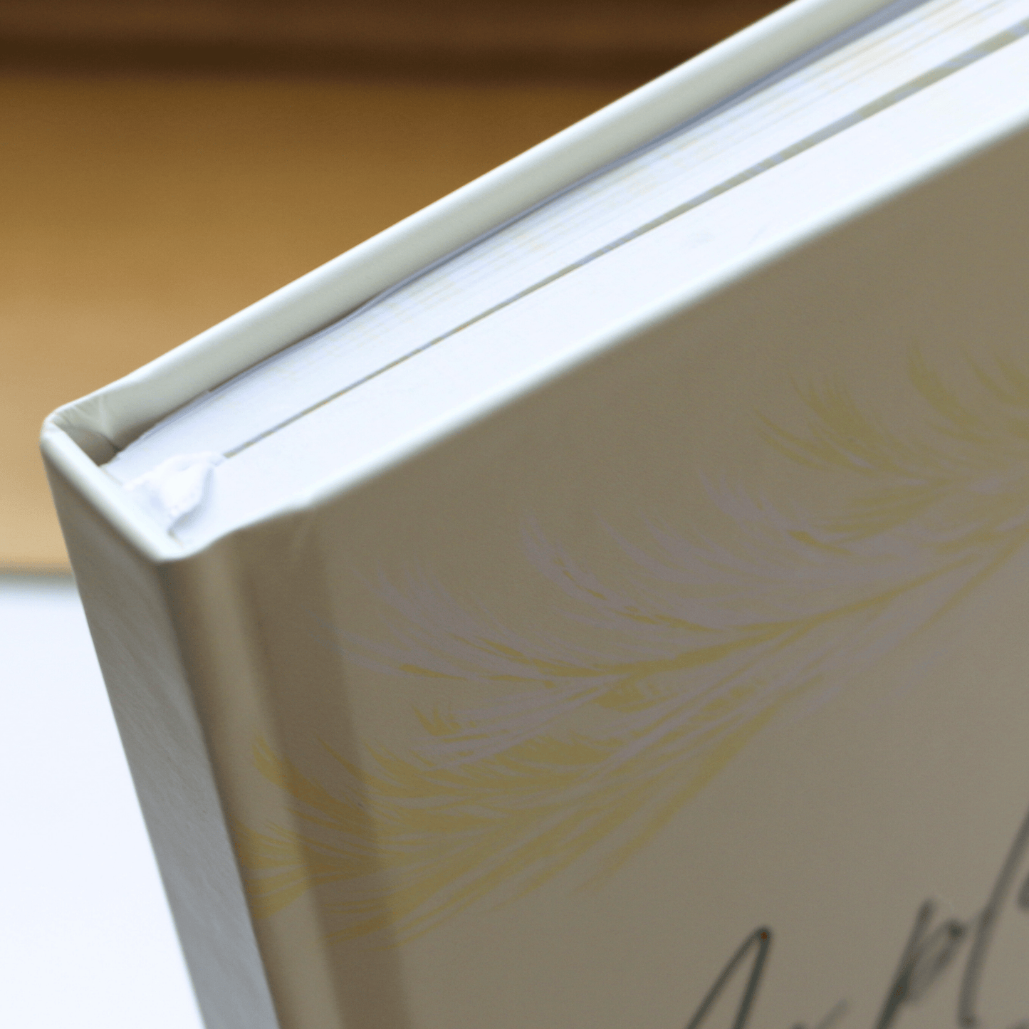 Close-up of a butter yellow book with a feather design on a light background